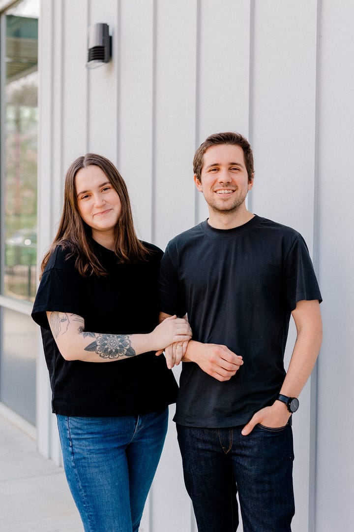 Locking Arms Owners standing in front of a white wall interlocking arms