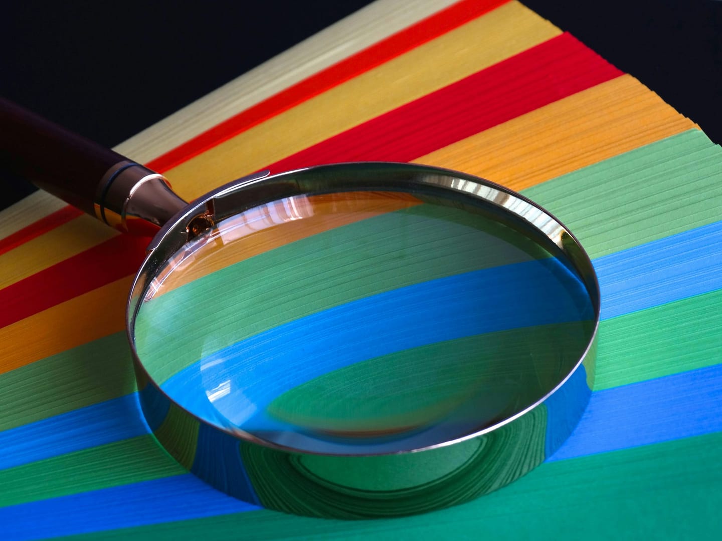 A magnifying glass on a colorful book, representing the deeper look we take at our clients' websites and search engine optimization.